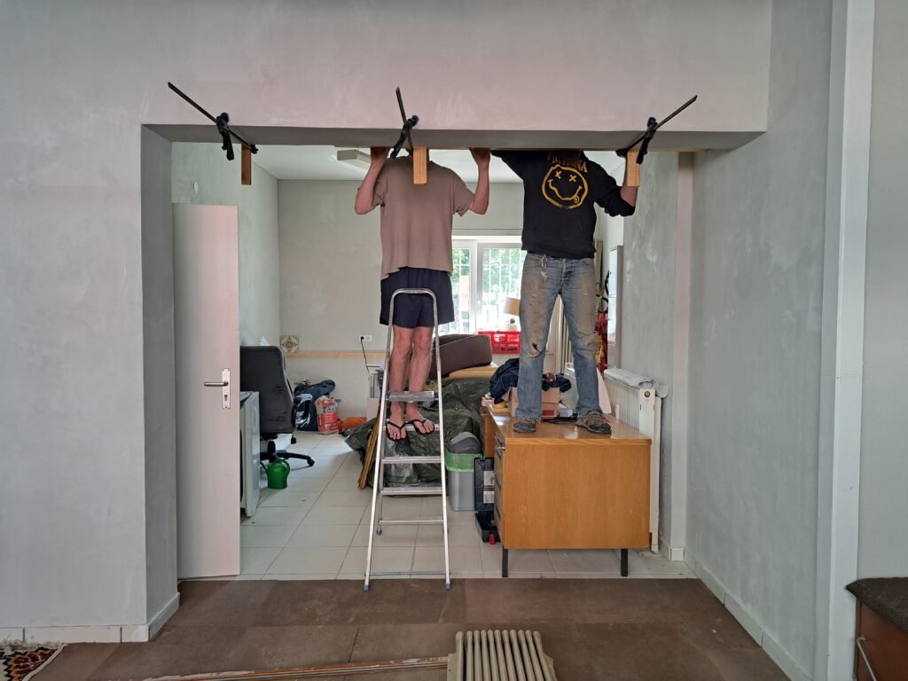 Zwei Menschen arbeiten auf Leitern im noch unfertigen Ladenlokal.