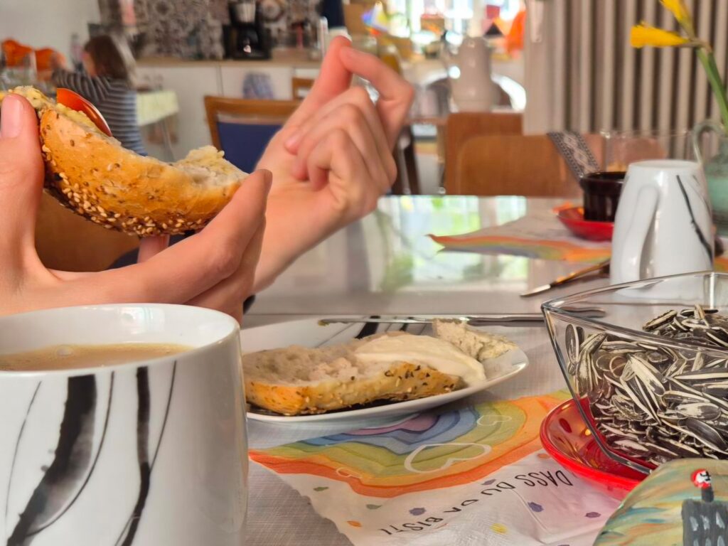 Beim ‚Frühstück gegen rechts‘ im frohnzimmer gestikuliert eine Person im Gespräch und hält mit der anderen Hand ein Brötchen.